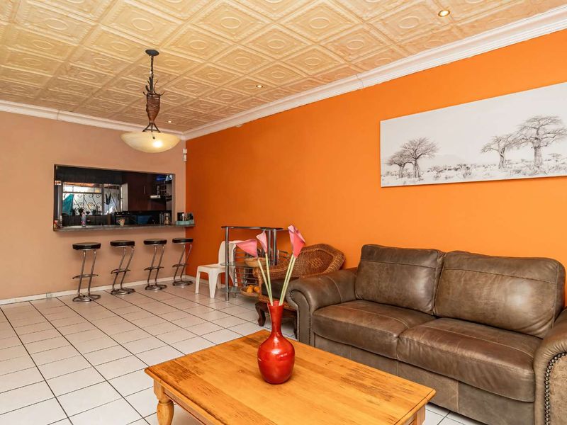 Open plan living area featuring tiled flooring, a decorative coffered ceiling, and a breakfast bar connecting to the kitchen space.
