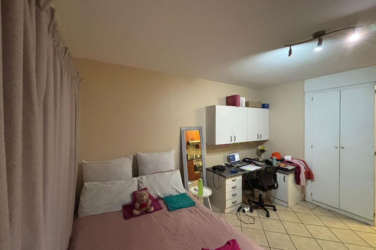 A bedroom featuring tiled flooring, built-in cabinetry, and a built-in desk area with overhead storage units.