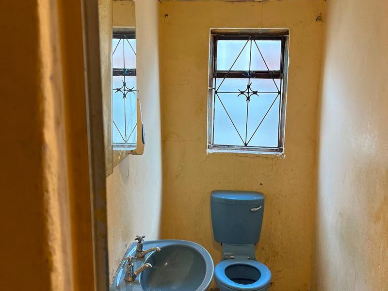 A small, dated bathroom featuring a blue pedestal basin and toilet, requiring significant renovation and cosmetic updates to improve its condition.