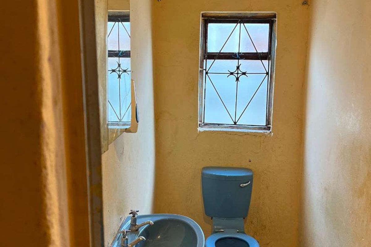 A small, dated bathroom featuring a blue pedestal basin and toilet, requiring significant renovation and cosmetic updates to improve its condition.