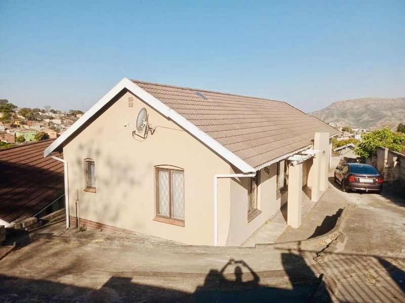 A detached residential house featuring a tiled roof, concrete driveway, and security-fitted windows, situated in a suburban neighborhood setting.