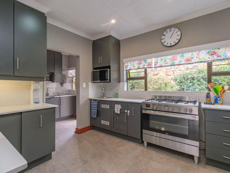 Modern kitchen featuring dark grey cabinetry, stone countertops, subway tile backsplash, and a stainless steel gas stove with oven.