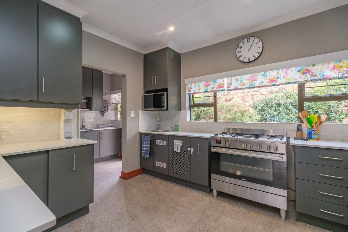 Modern kitchen featuring dark grey cabinetry, stone countertops, subway tile backsplash, and a stainless steel gas stove with oven.