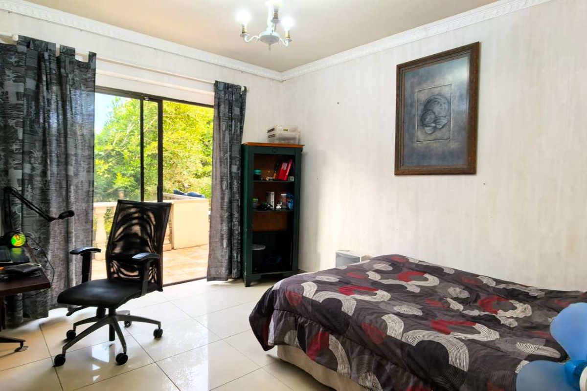 A bedroom featuring tiled flooring, ceiling cornice, and a sliding glass door providing access to an outdoor area.