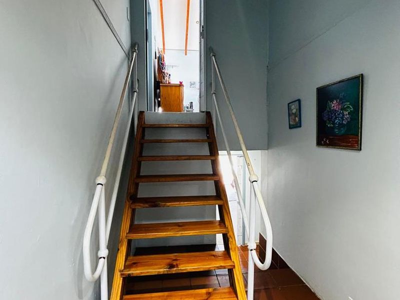 A functional hallway featuring a timber staircase with metal handrails and tiled flooring, providing access to the upper level of the home.