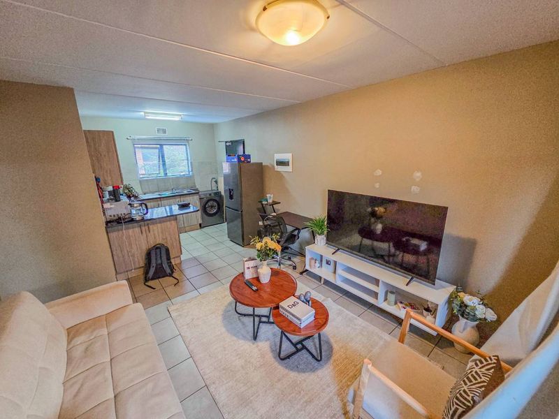 Open-plan living area featuring a combined kitchen and lounge space with tiled flooring and neutral wall finishes.