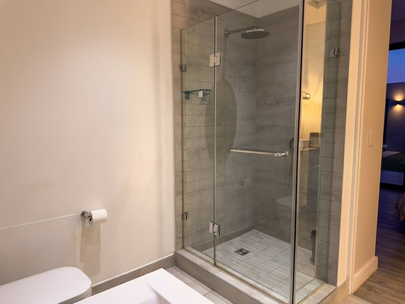 Modern bathroom featuring a glass-enclosed walk-in shower with a rain shower head and contemporary tiled finishes.