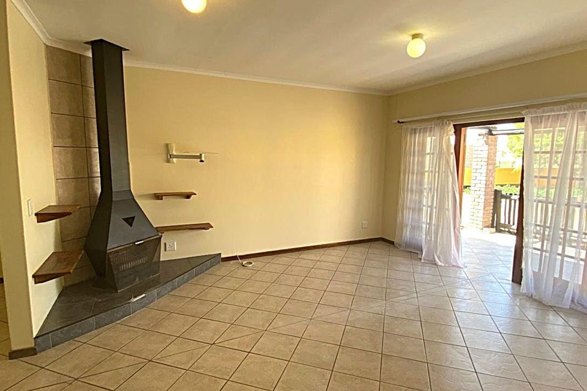 Spacious living room featuring a built-in fireplace with tiled hearth and large glass sliding doors providing access to the outdoor patio area.