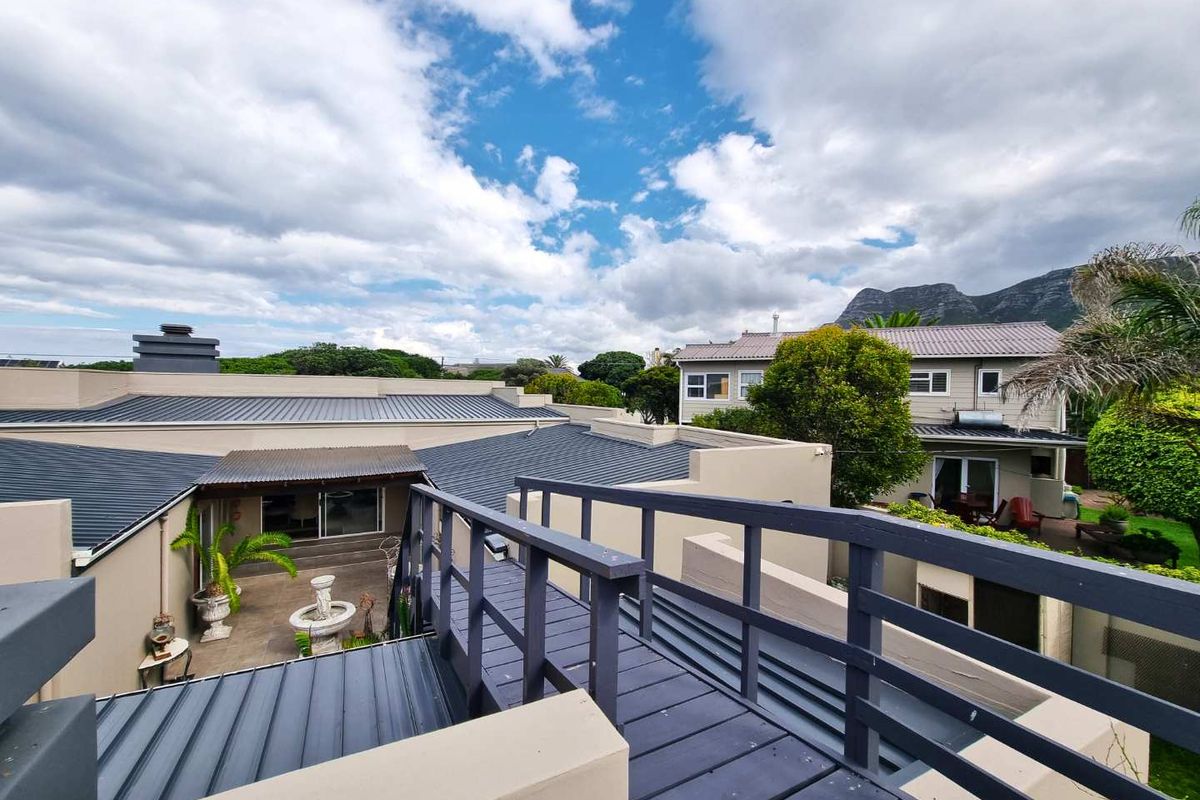 Elevated view overlooking the property's rear courtyard, featuring a metal roof, wooden walkway, and surrounding residential landscape.