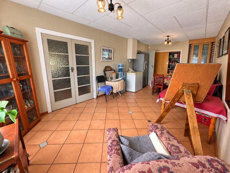 Open plan living area featuring tiled flooring, drop ceiling tiles, and double french doors leading to adjacent spaces.