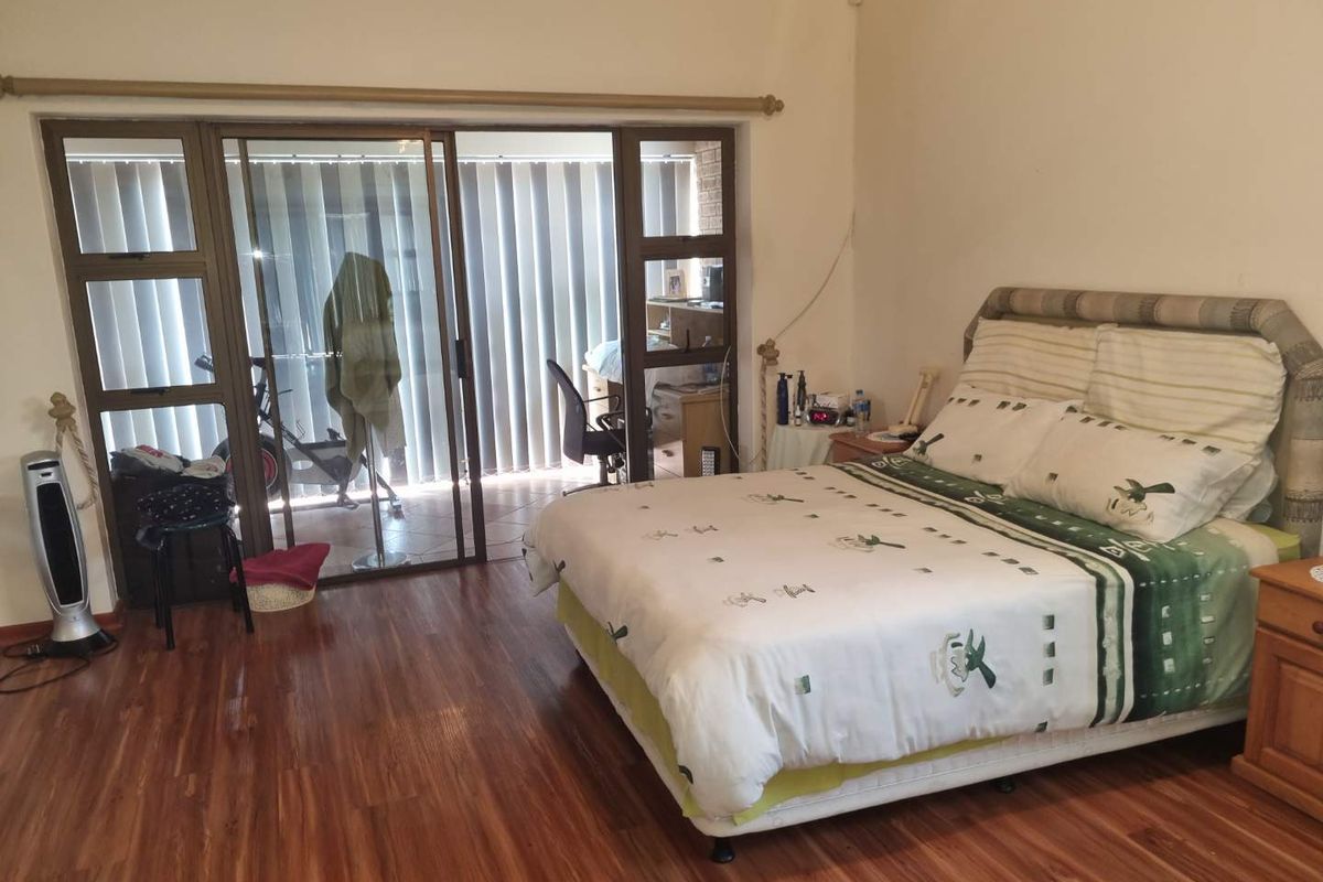 Spacious bedroom featuring wood-look laminate flooring and large sliding glass doors providing access to an adjoining patio area.