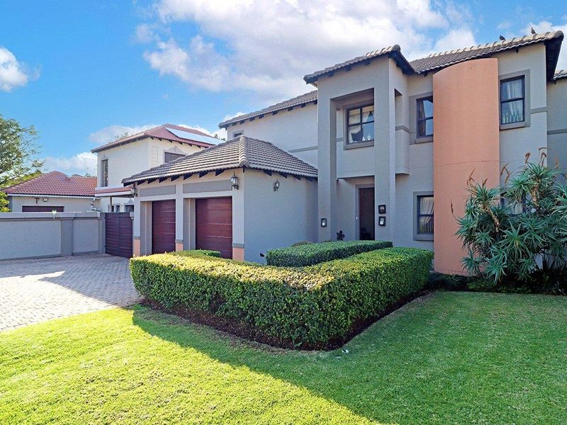 A well-maintained double-story residential property featuring a paved driveway, double garage, and manicured front garden.