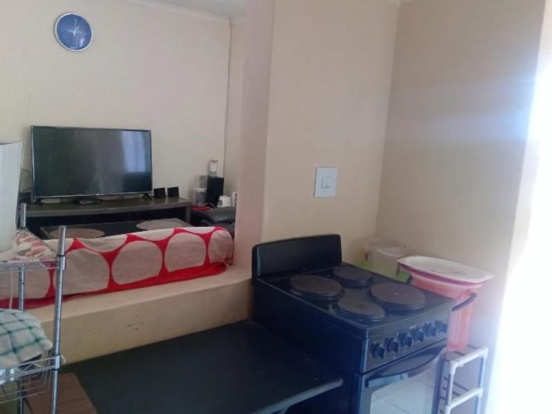 Open plan living area featuring a raised floor section and a compact kitchen space with a freestanding electric stove.