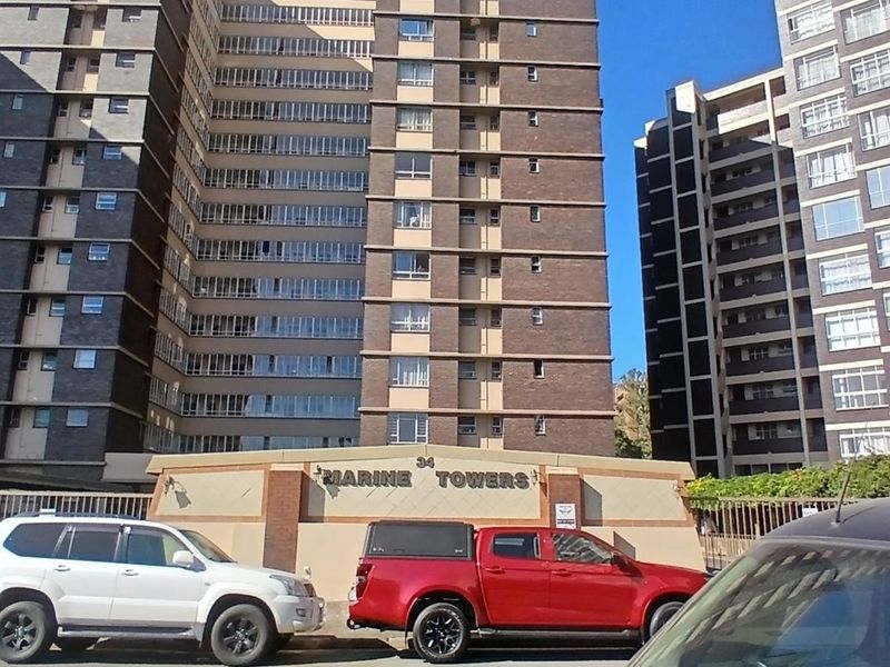 Front exterior view of Marine Towers apartment complex featuring a brick facade and secure gated entrance.