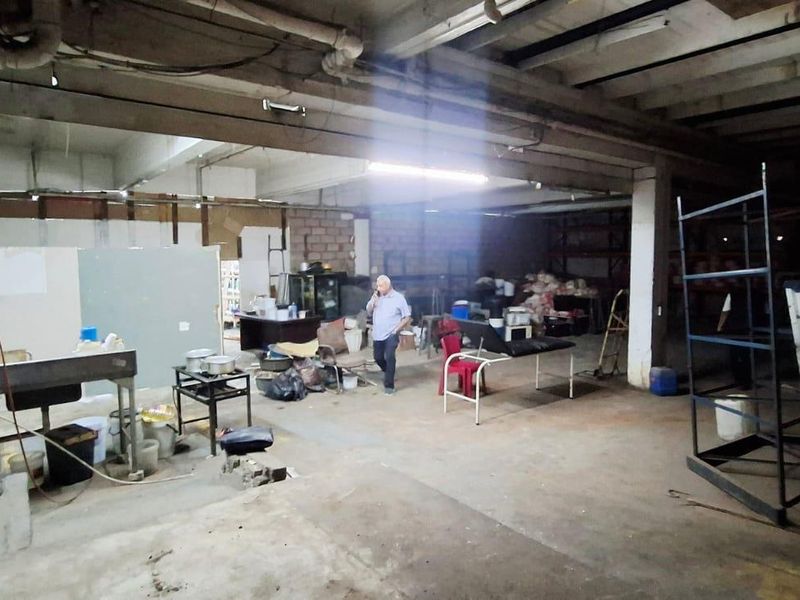 Large industrial utility space featuring exposed concrete ceilings, structural beams, and raw concrete flooring, suitable for workshop or storage conversion.