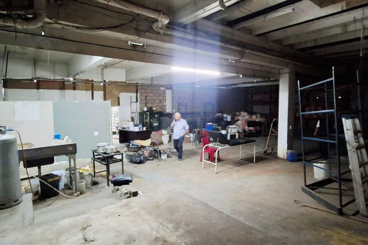 Large industrial utility space featuring exposed concrete ceilings, structural beams, and raw concrete flooring, suitable for workshop or storage conversion.