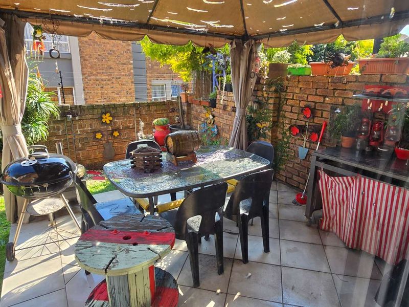 Covered outdoor patio area featuring tiled flooring and a brick boundary wall, providing a functional space for outdoor dining and relaxation.