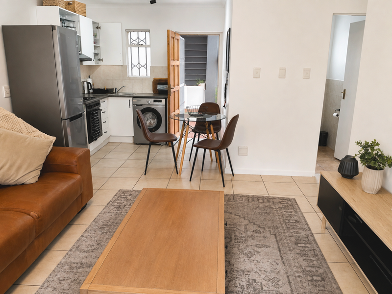 Open-plan living and kitchen area featuring tiled flooring, functional cabinetry, and direct access to an outdoor space.