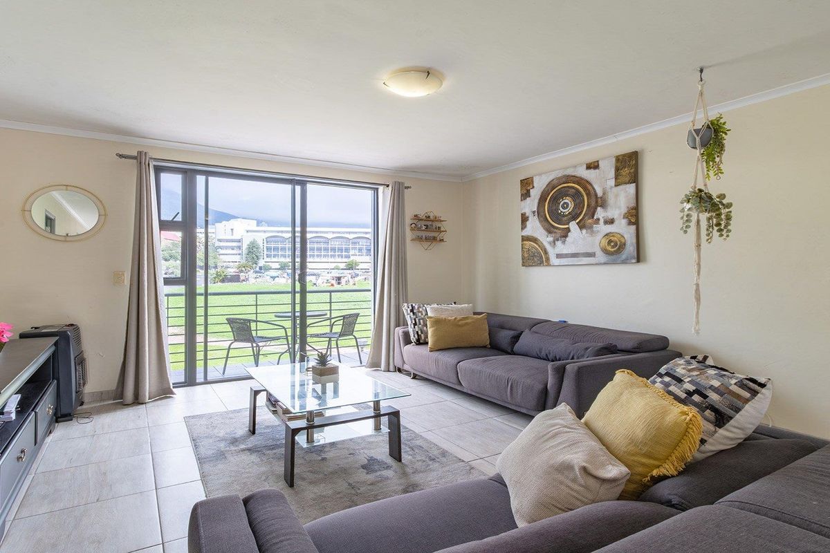 A bright living room featuring tiled flooring and a large sliding glass door that provides access to an outdoor balcony area.