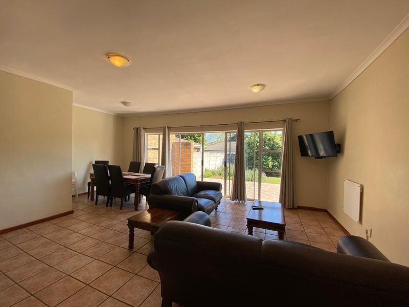 Spacious open-plan living and dining area featuring tiled flooring and large sliding glass doors that provide direct access to the outdoor patio.