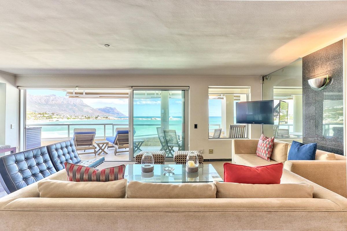 Spacious living room featuring a stone accent wall and large sliding glass doors that open to a balcony with panoramic ocean and mountain views.