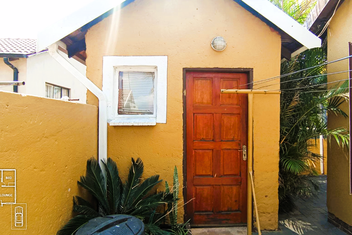 Exterior view of a side entrance featuring a solid timber door, small window, and external wall-mounted lighting.
