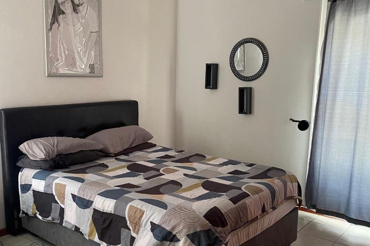 A bedroom featuring tiled flooring, a wall-mounted air conditioning unit, and a sliding door providing access to the exterior.
