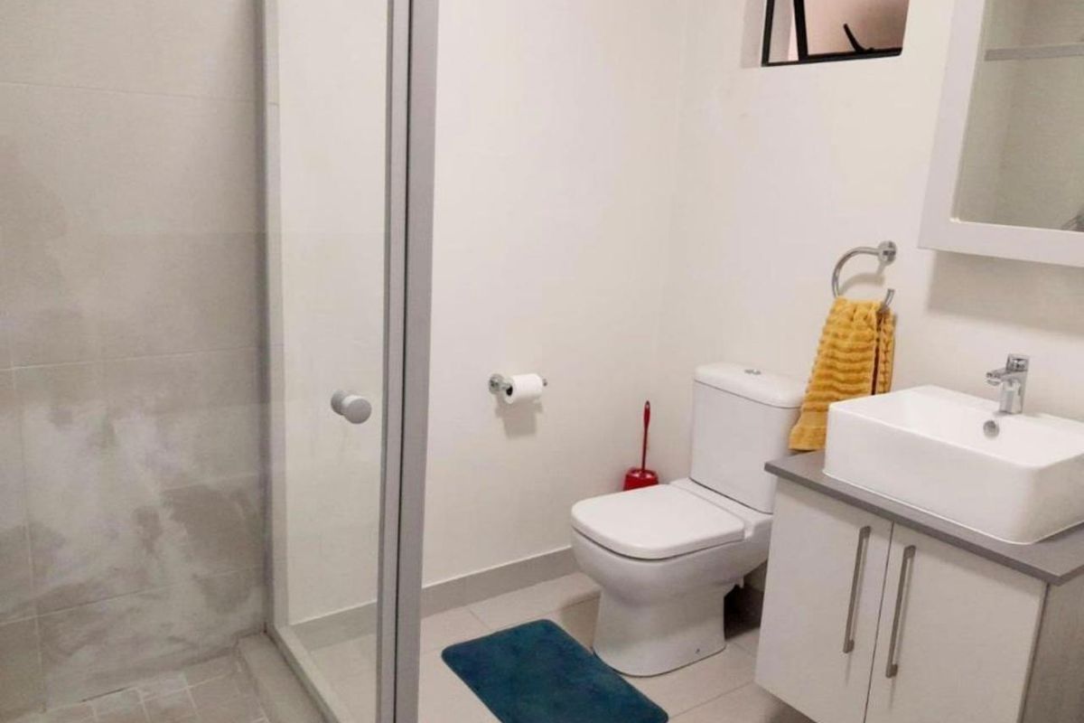 A functional bathroom featuring a glass-enclosed shower, a modern vanity with a vessel sink, and a standard toilet.