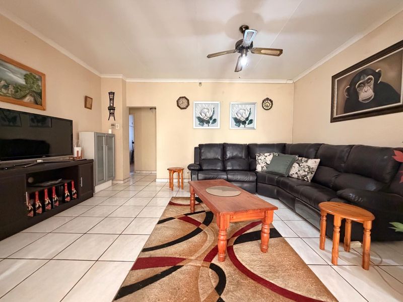 A spacious living room featuring neutral wall tones, tiled flooring, and a central ceiling fan, providing a functional and comfortable family living area.