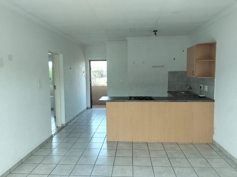 Open plan kitchen and living area featuring tiled floors, built-in cabinetry with hob, and direct access to an outdoor balcony area.