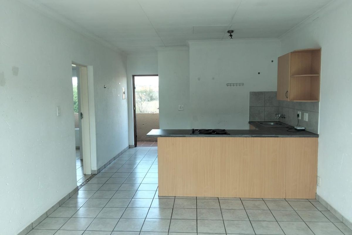 Open plan kitchen and living area featuring tiled floors, built-in cabinetry with hob, and direct access to an outdoor balcony area.
