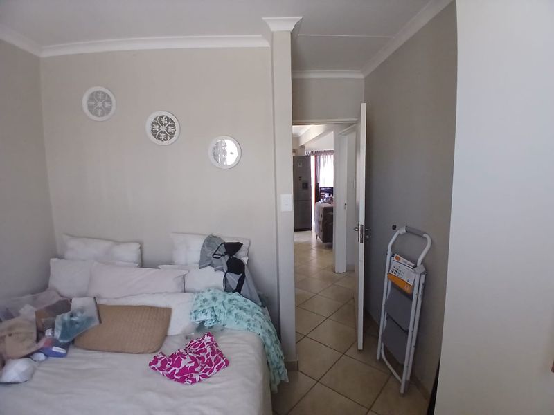 A bedroom featuring tiled flooring and coving, with a doorway leading to an adjacent living area.