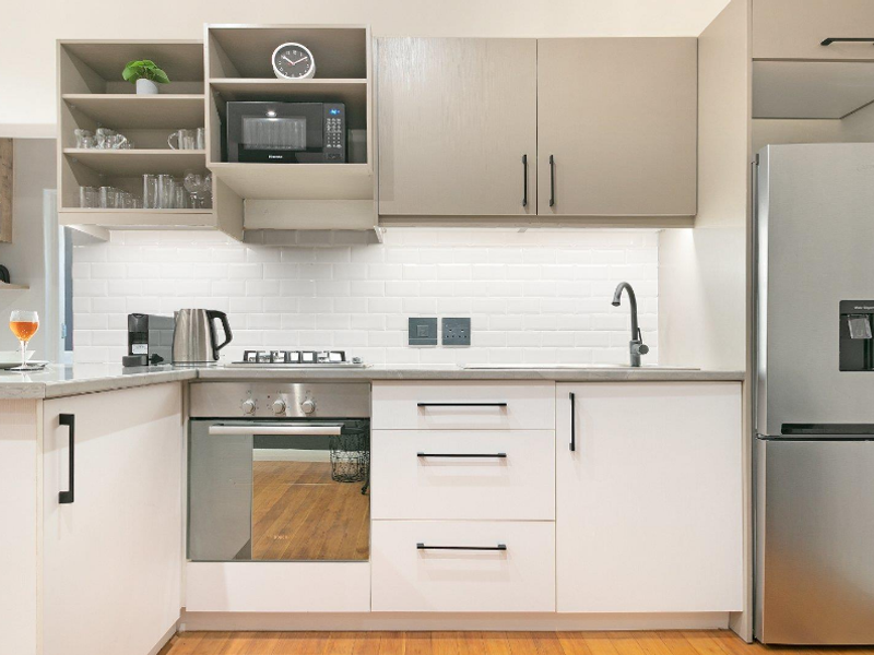 Modern kitchen featuring clean white subway tile backsplash, sleek two-tone cabinetry, integrated gas hob, built-in oven, and high-quality stone countertops.