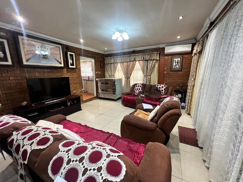 Spacious living room featuring exposed brick walls, tiled flooring, and a split-system air conditioner, offering a warm and functional living space.