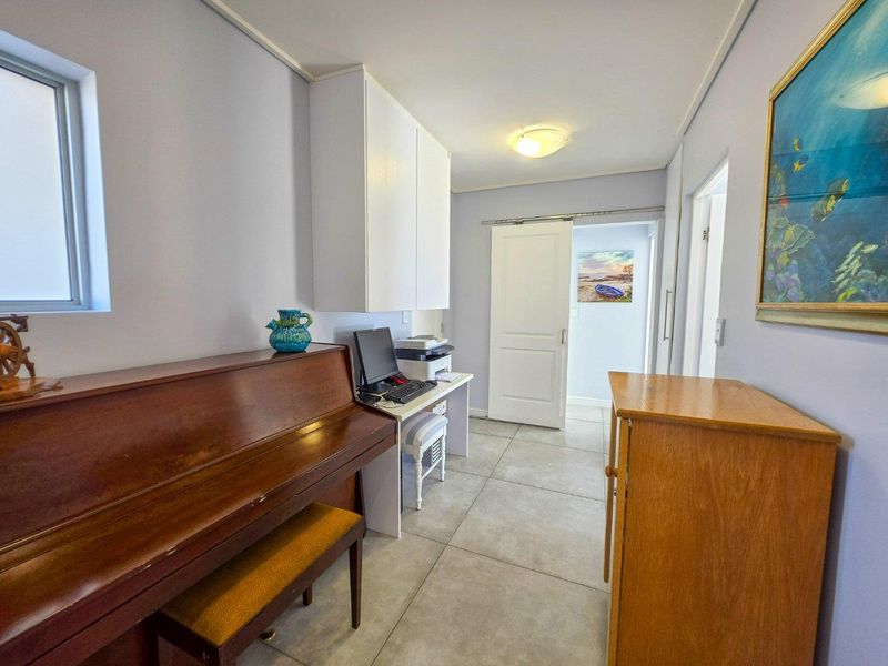 A functional home office space featuring tiled flooring, built-in wall cabinetry, and a sliding door leading to an adjacent room.