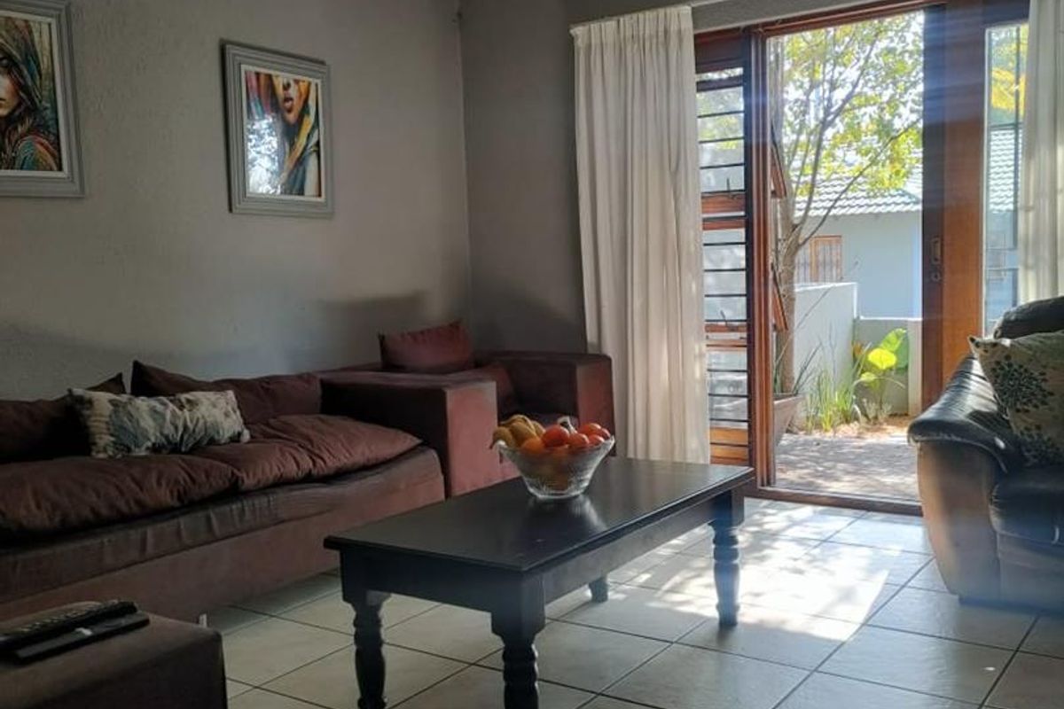 A living room featuring tiled flooring and a sliding glass door that provides access to an outdoor patio area.