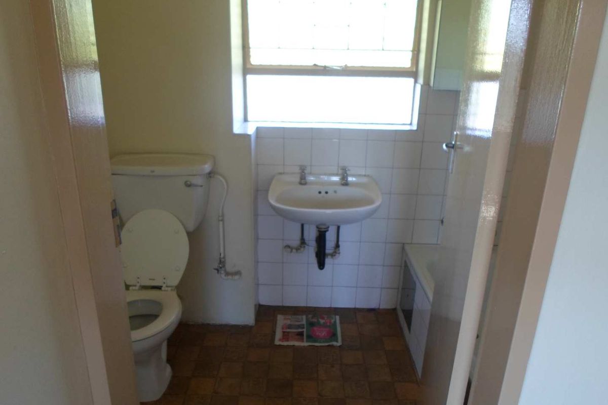 A functional bathroom featuring a standard toilet, pedestal basin, and bathtub, requiring cosmetic updates to modernize the space.