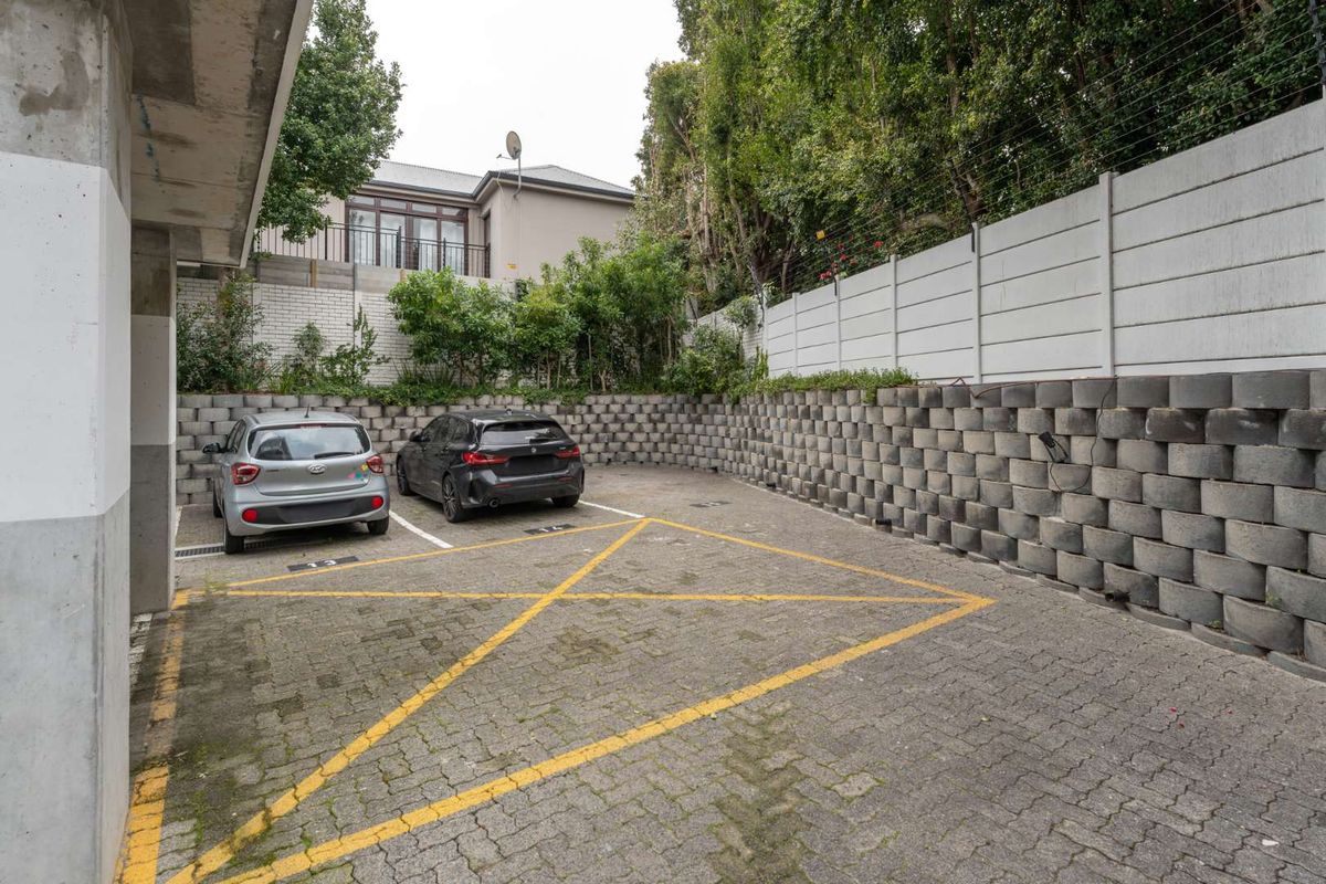A paved outdoor parking area featuring a structured retaining wall and secure perimeter fencing.