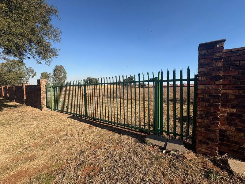 A view of the vacant residential land featuring a secure steel palisade fence and brick boundary wall.