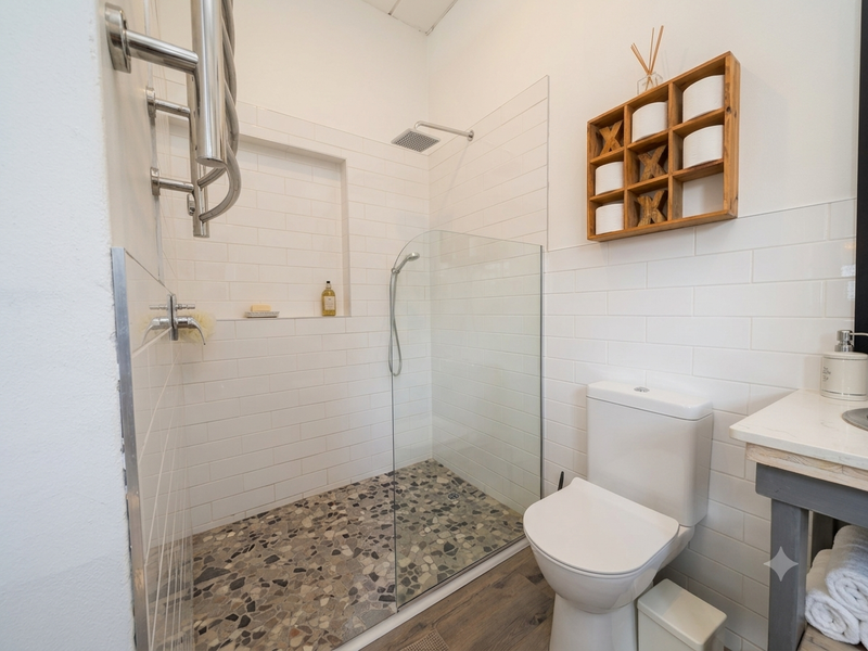 Modern bathroom featuring a walk-in shower with pebble flooring, subway wall tiles, a built-in niche, and a heated towel rail.