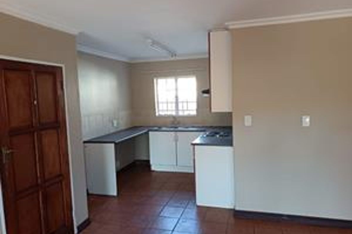 A functional, empty kitchen featuring built-in cabinetry, laminate countertops, a stainless steel sink, and ceramic tile flooring.
