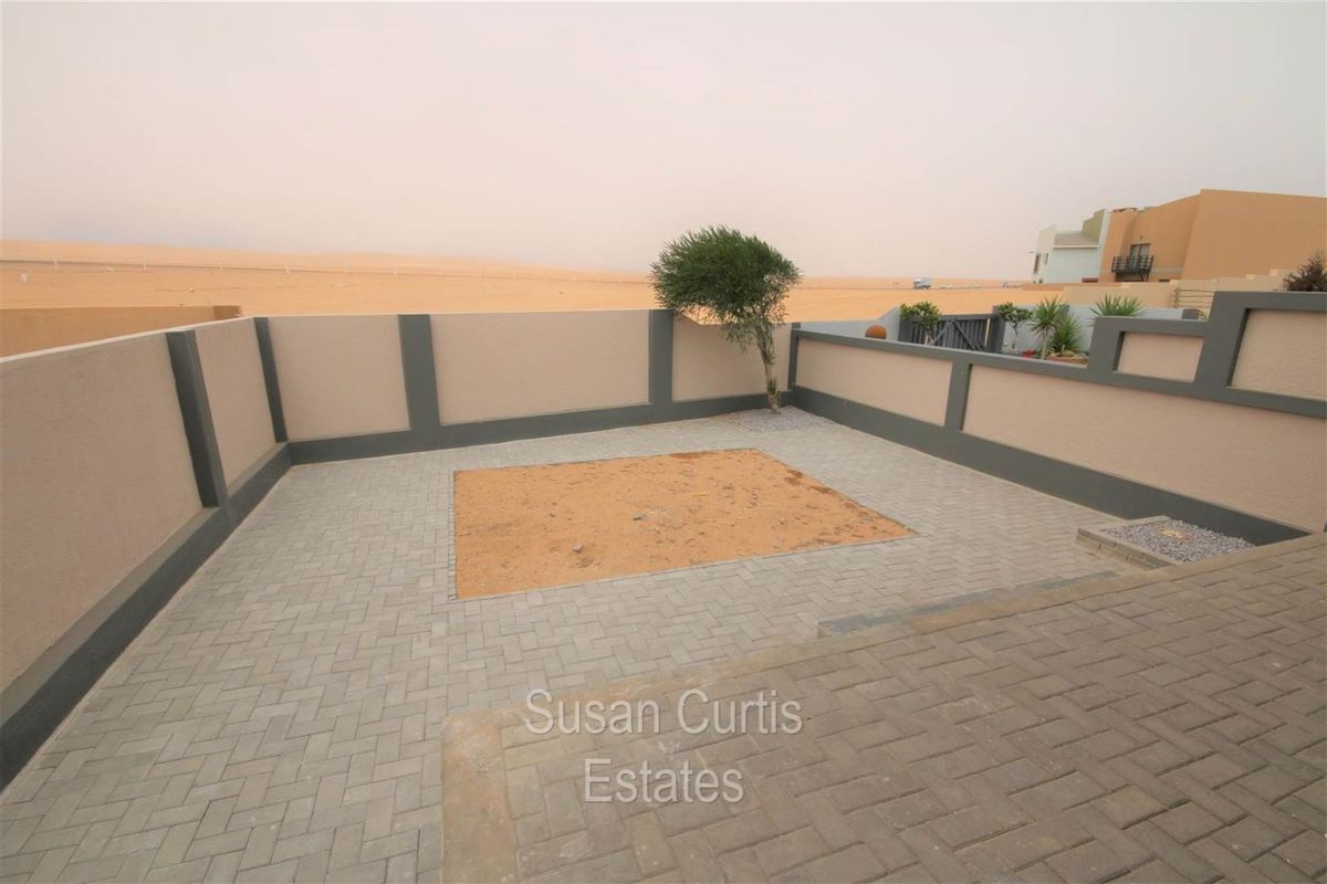 A private rear courtyard featuring paved flooring and a perimeter boundary wall, offering an open outlook over the surrounding desert landscape.