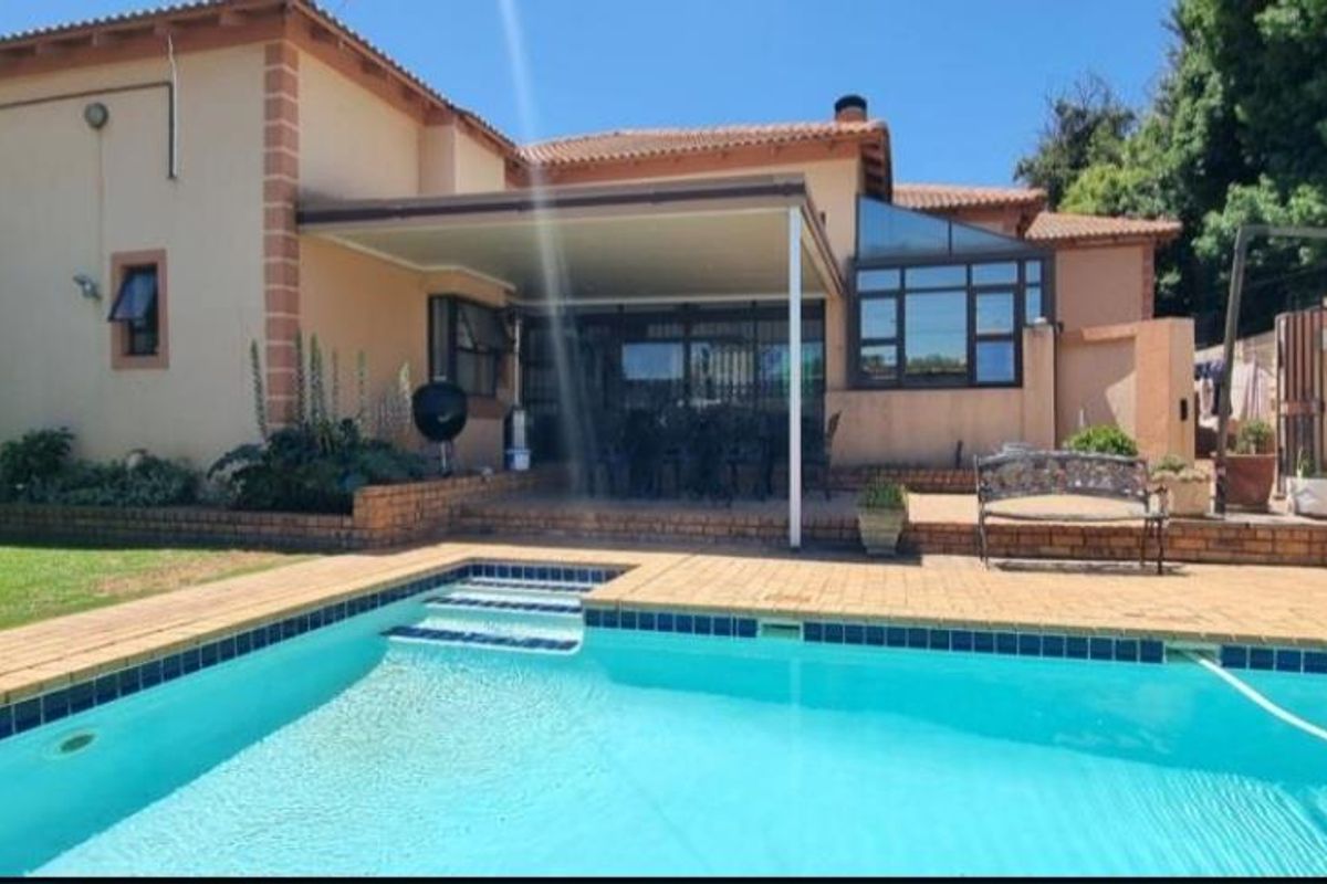 Rear view of the property featuring a swimming pool, paved pool deck, and a covered patio area attached to the main house structure.