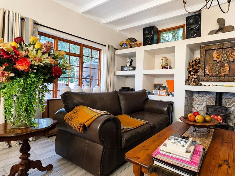 Cozy living room featuring exposed ceiling beams, a fireplace with decorative tiling, and built-in shelving units, complemented by large timber-framed windows.