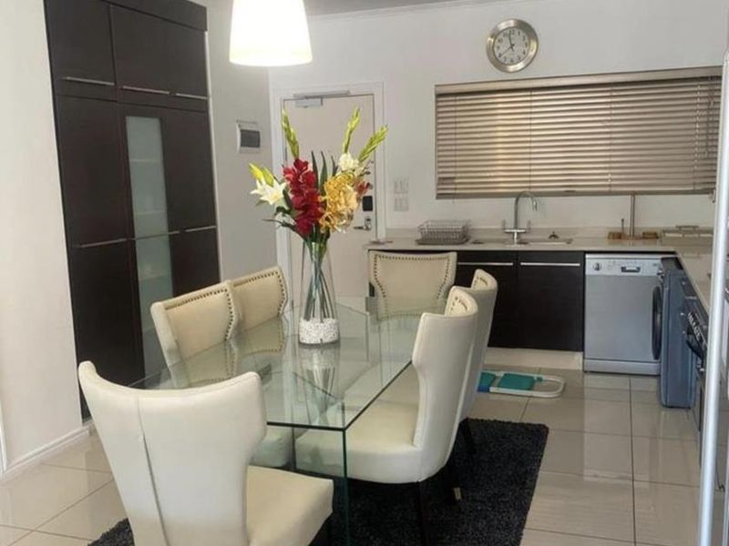 Open-plan living and kitchen area featuring modern dark cabinetry, tiled flooring, and a functional kitchen layout with integrated sink and appliances.