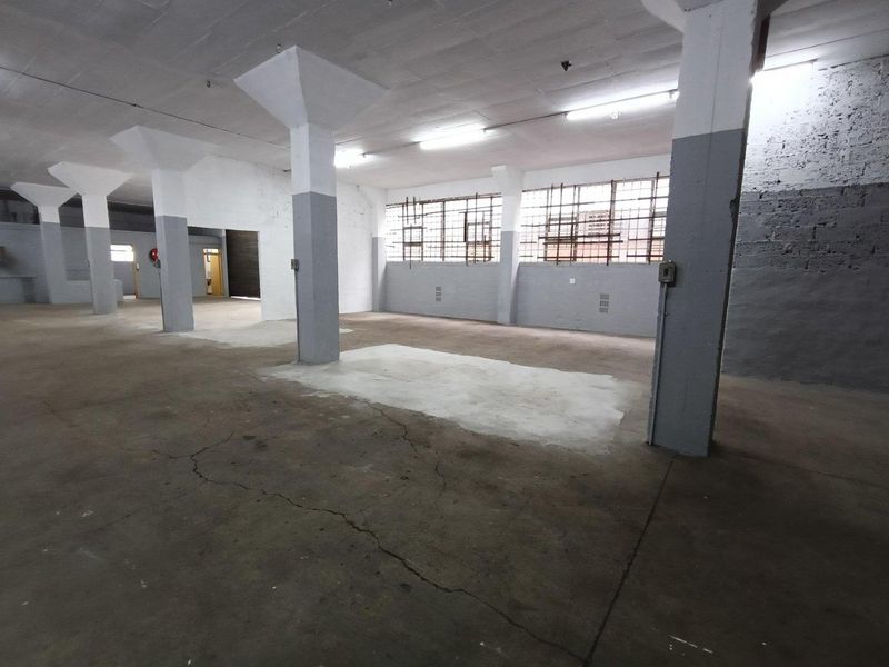 Spacious industrial utility area featuring concrete flooring, structural columns, and large steel-framed windows, offering a versatile open-plan layout for various commercial uses.