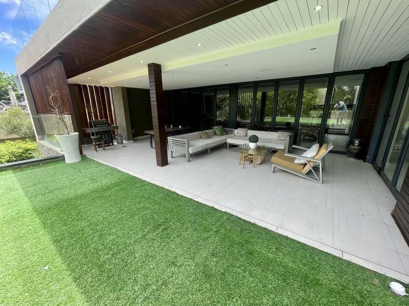 A spacious covered patio featuring tiled flooring, timber ceiling accents, recessed lighting, and seamless access to the interior through large sliding glass doors.