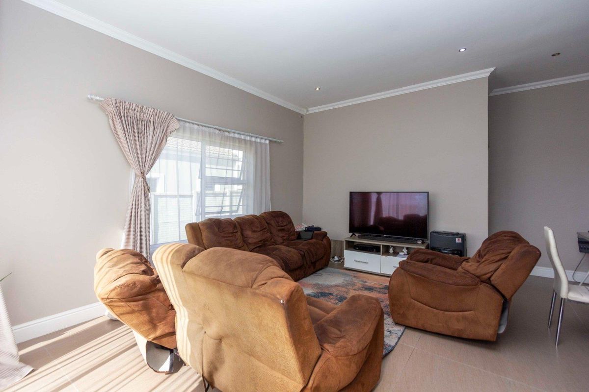 A well-maintained living room featuring neutral wall tones, tiled flooring, recessed downlighting, and crown molding.
