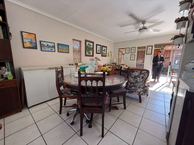 Open plan living and dining area featuring ceramic floor tiles, a ceiling fan, and direct access to the rear outdoor space through a sliding door.