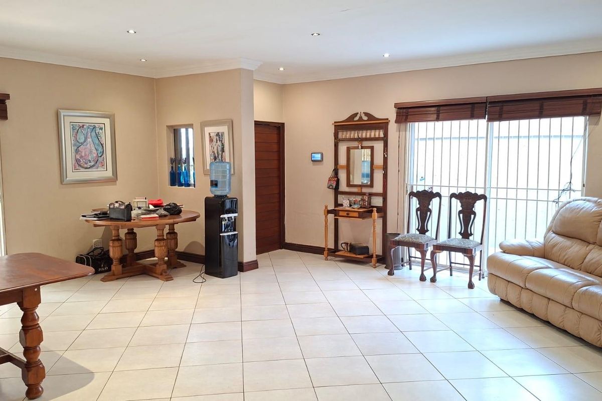 Spacious living area featuring neutral tiled flooring, recessed downlighting, and large sliding glass doors with security bars providing access to the exterior.